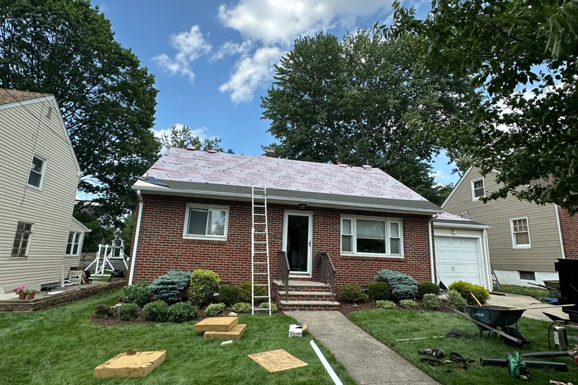 Roofer repairing shingles and step flashing on a split level home in Paramus NJ