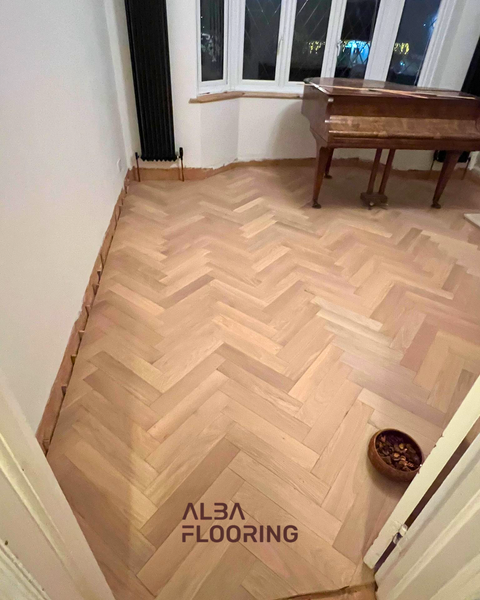 Close view of completed herringbone engineered wood floor near fireplace and doorway