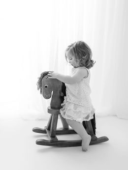 Baby on rocking horse during black and white milestone session