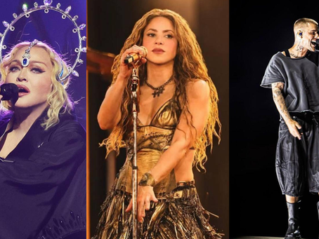 Madonna à esquerda, Shakira no meio e Justin Bieber à direita. Os três com microfone e cantando. 