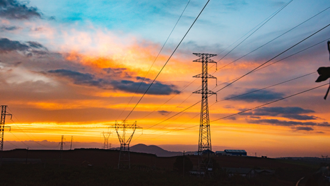 Torres de energia elétrica ao pôr do sol, representando o Mercado Livre de Energia e o Ambiente de Contratação Livre (ACL) no setor elétrico brasileiro.
