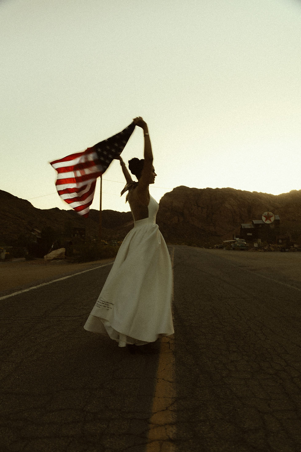 Bride holding an American flag in the Nevada desert at sunset on a desert road at Nelson Ghost Town.