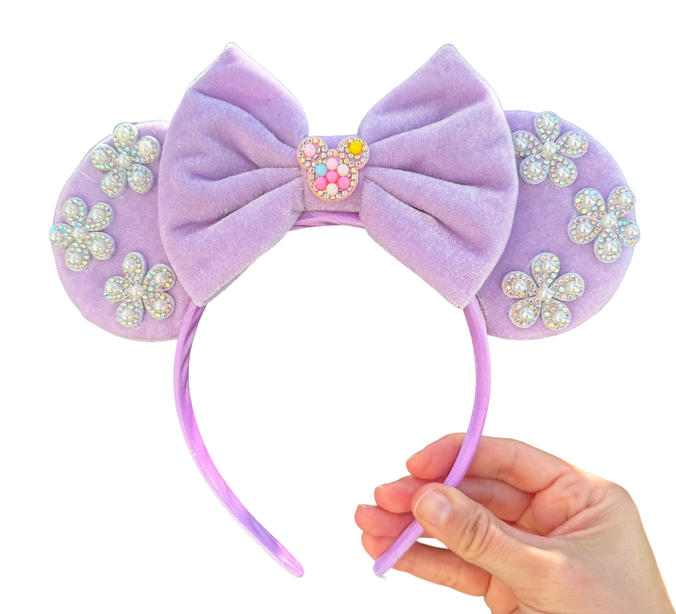 A light purple handband with a large purple bow and mossy green colored flower accents.
