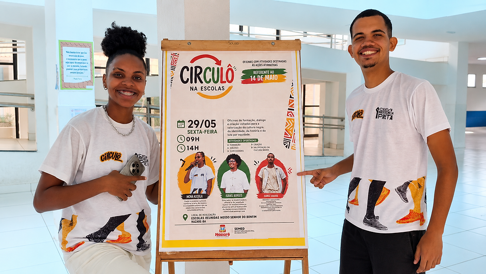 Dois jovens sorridentes apontam para cartaz do Círculo na Escolas num corredor escolar claro; destaque para 29/05 e 14 de maio.