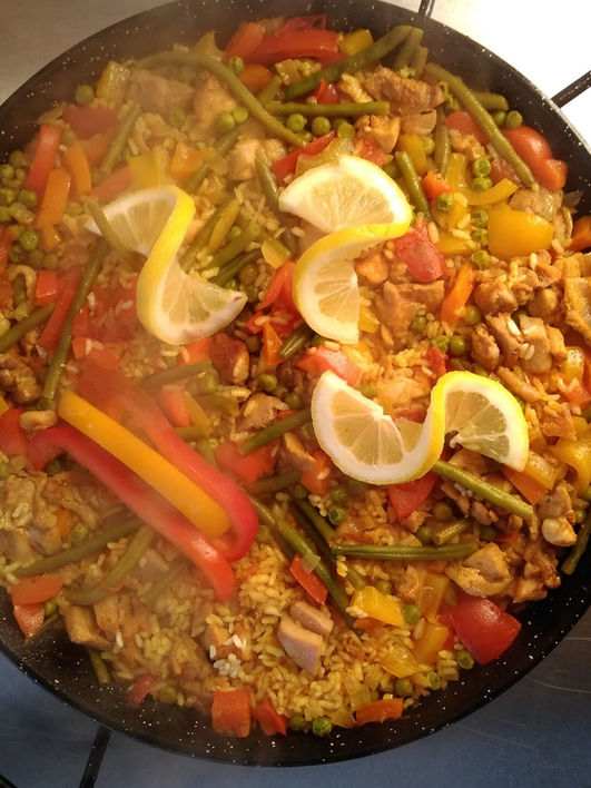 Leckeres Paella-Gericht mit Hühnchen, Gemüse und Zitrone