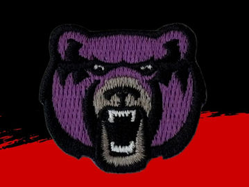 Small embroidered patch depicting a bear's face in purples and greys, with an open mouth and visible teeth.