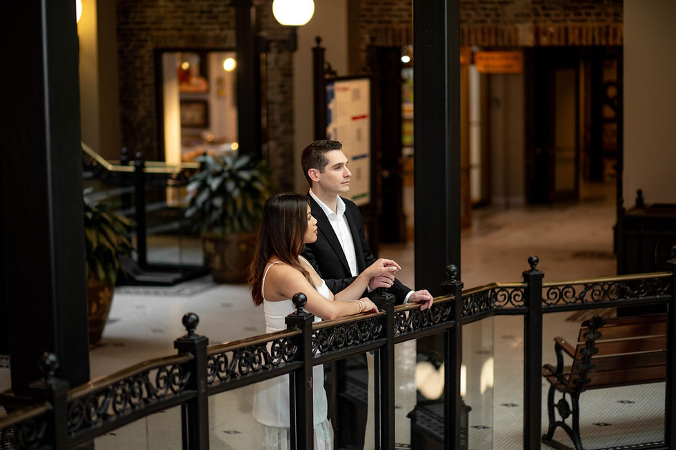 Black and white engagement photos of a couple holding hands, sharing a romantic moment, and posing together in an elegant hallway.