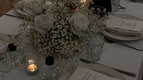 Bride and groom exit at night surrounded by guests holding sparklers, with fireworks in the sky.