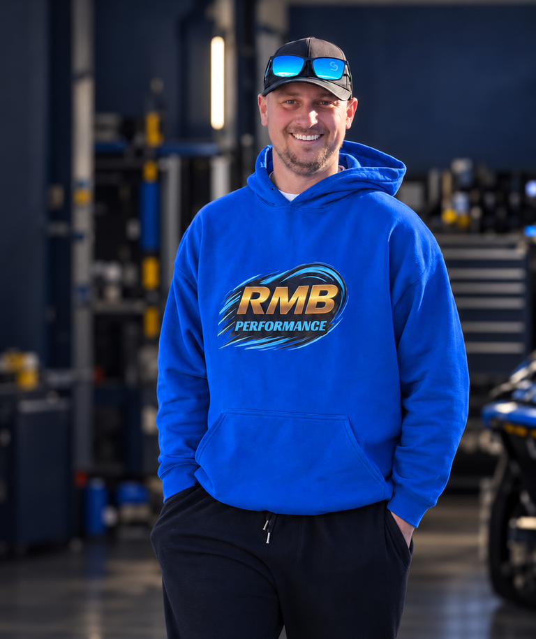 Portrait of the RMB PERFORMANCE business owner in a bright blue branded hoodie, standing in a performance garage