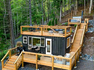 Rustikale Tiny Home Küche mit massiven Holzfronten, Gasherd, Holzarbeitsflächen, Treppenschubladen zur Loft-Ebene und großen Fenstern, die Tageslicht ins Innere fallen lassen