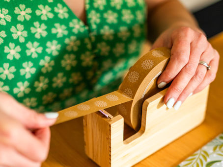 A paper tape with flowers design in a bamboo tape dispenser.