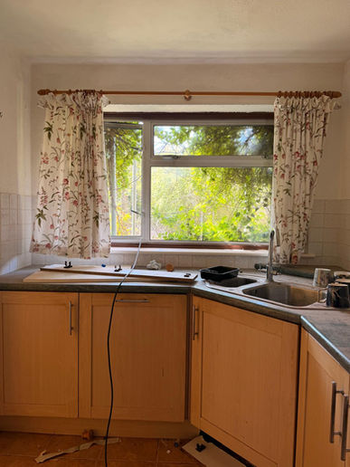 Existing kitchen with original cabinetry and window arrangement.