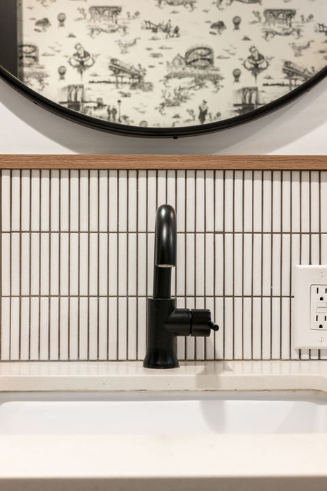 Black faucet against striped wall, round mirror above, Reno NV — Find Design