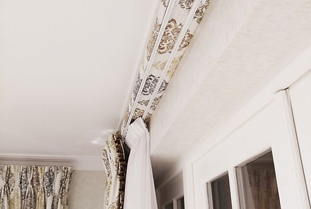 A cover board and Lava. A double track with a white net curtain at the back and a floral print curtain in front.