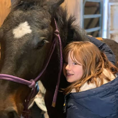 Girl hugging the neck of a black horse