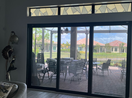 Custom decorative design for a set of 3 transoms on top of the living area slider. White textured frost, colored glossy texture and black lines.