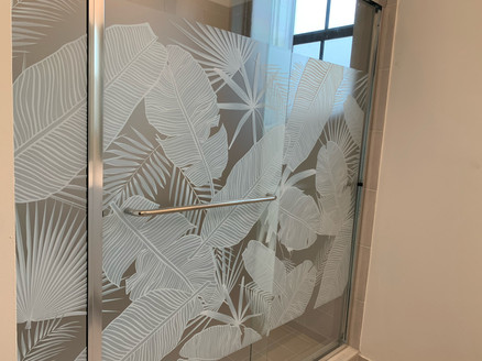 Horizontal shower enclosure design with tropical leaves. White frost and clear frost for the right amount of privacy. Decorative film also as the added benefit of hiding the marks of hard water on glass.