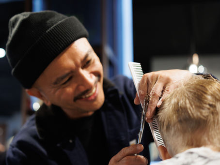 happy barber cutting child's hair