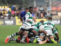 Zimbabwe rugby captain Hilton Mudariki lifts the Africa Cup trophy in celebration as the Sables qualify for the 2027 Rugby World Cup, ending a 34-year drought. Teammates cheer around him in their green-and-white kits at Mandela National Stadium in Kampala after a dramatic 30–28 win over Namibia.