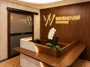 木目調の高級感ある「W PREMIUM LOUNGE」受付。白い胡蝶蘭と照明付きカウンターがある静かな室内。