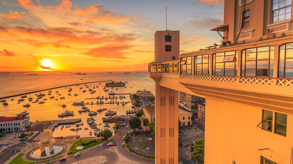 サルバドールの夕焼け、港に浮かぶ船と歴史的なエレベーター。オレンジ色の空に映える活気ある都市の風景。