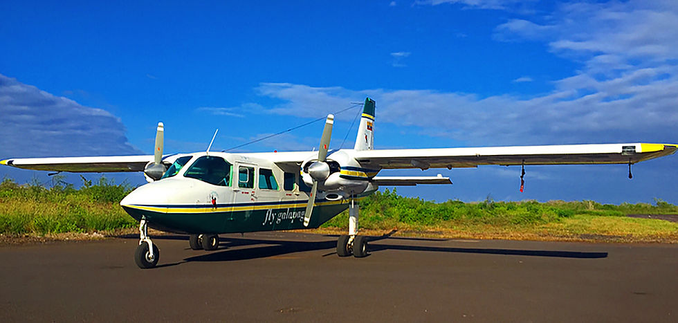 青空の下、滑走路に停まる双発プロペラ機。胴体にFly Galapagosの文字、背後に緑の草地が広がる。