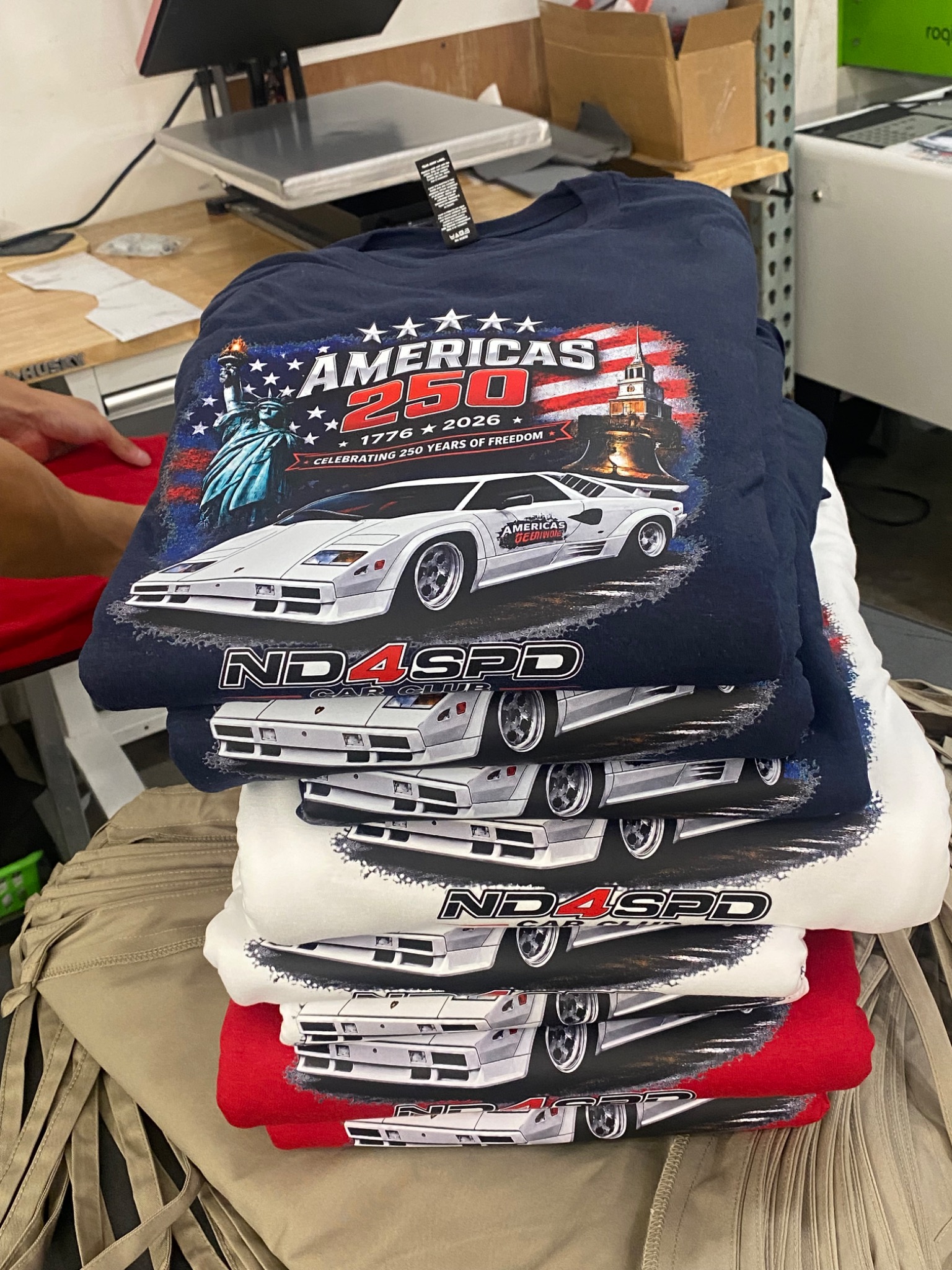 Stack of ND4SPD America’s 250 custom shirts with detailed full-color heat transfer artwork