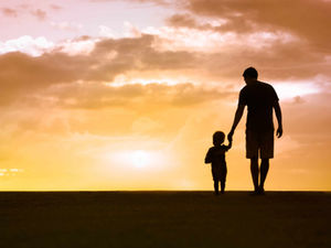 A father walking alongside their child. 