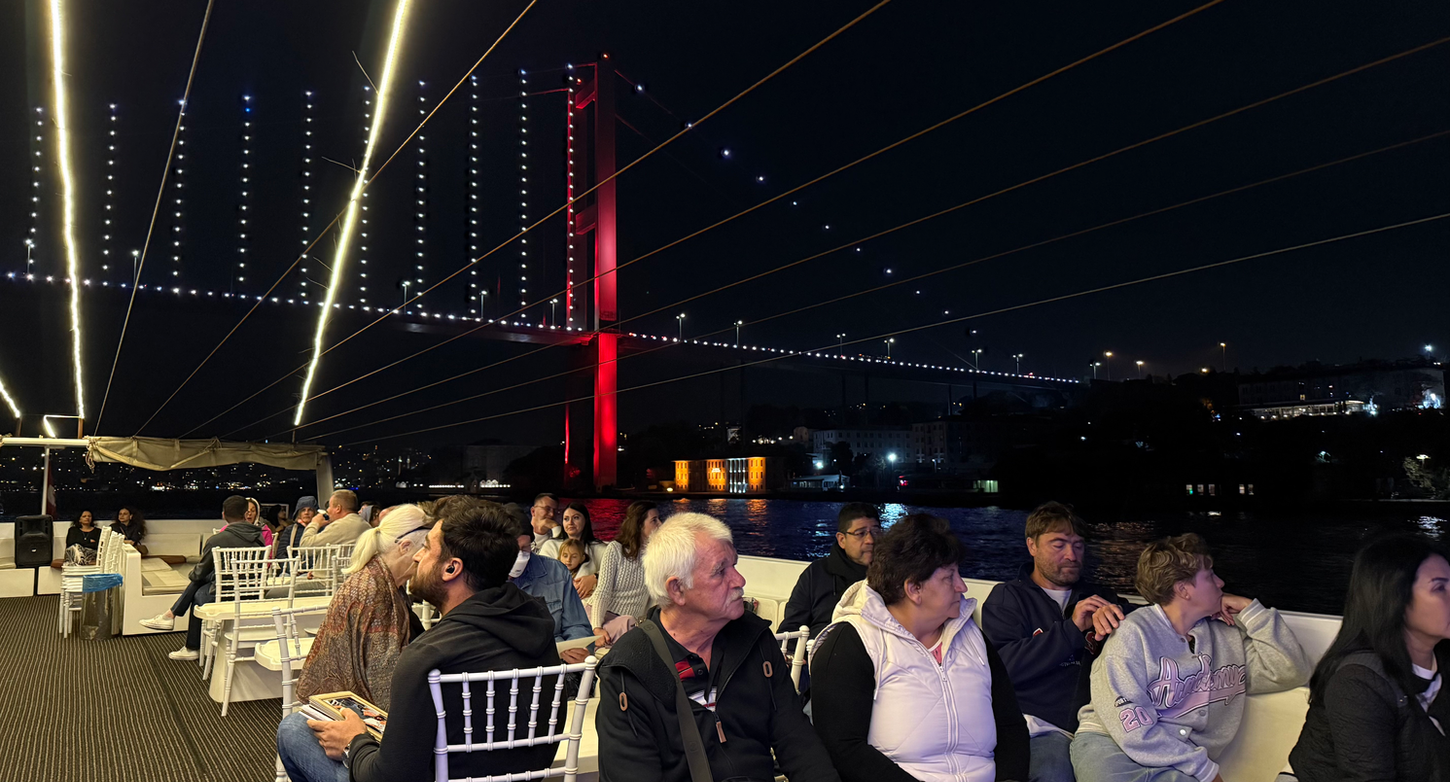 Group of travelers on Istanbul night cruise with Bosphorus night skyline