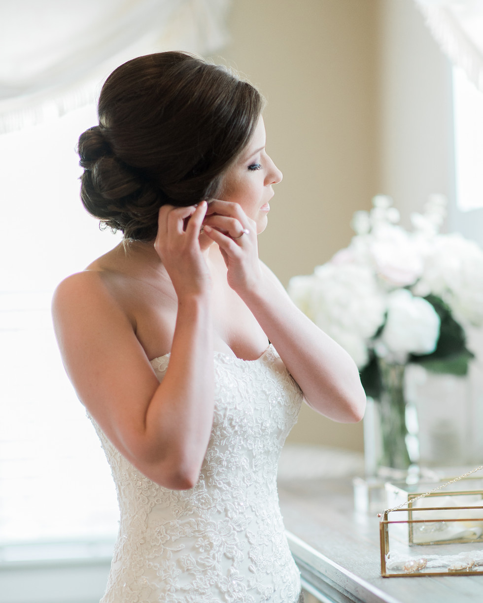Bride putting earrings on looking away from camera