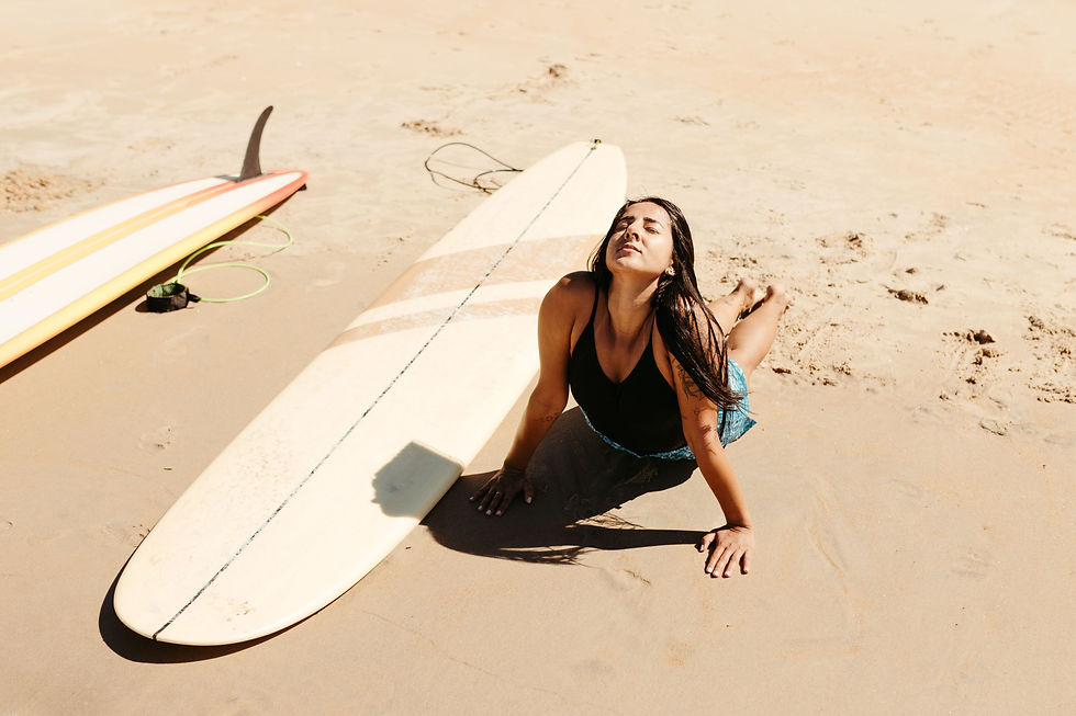Woman practicing yoga beside a surfboard during a surf and yoga stay in Hiriketiya, Sri Lanka