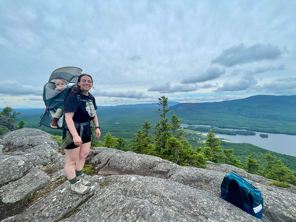 baby in carrier and mother at top of mountain