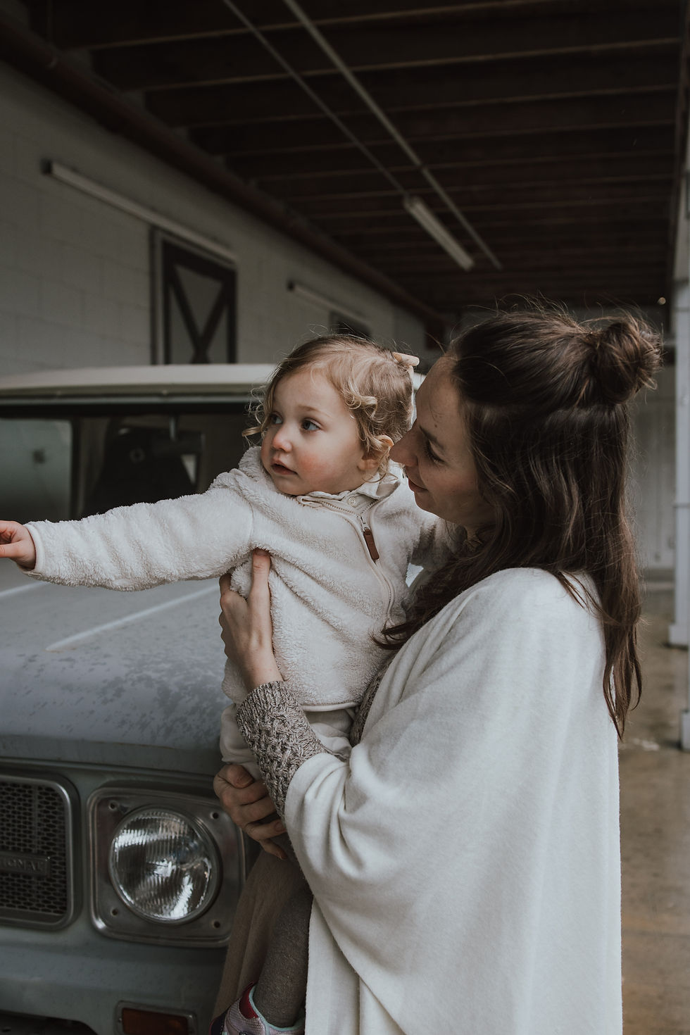 a mother and daughter seeking shelter in a horse barn out of the rain