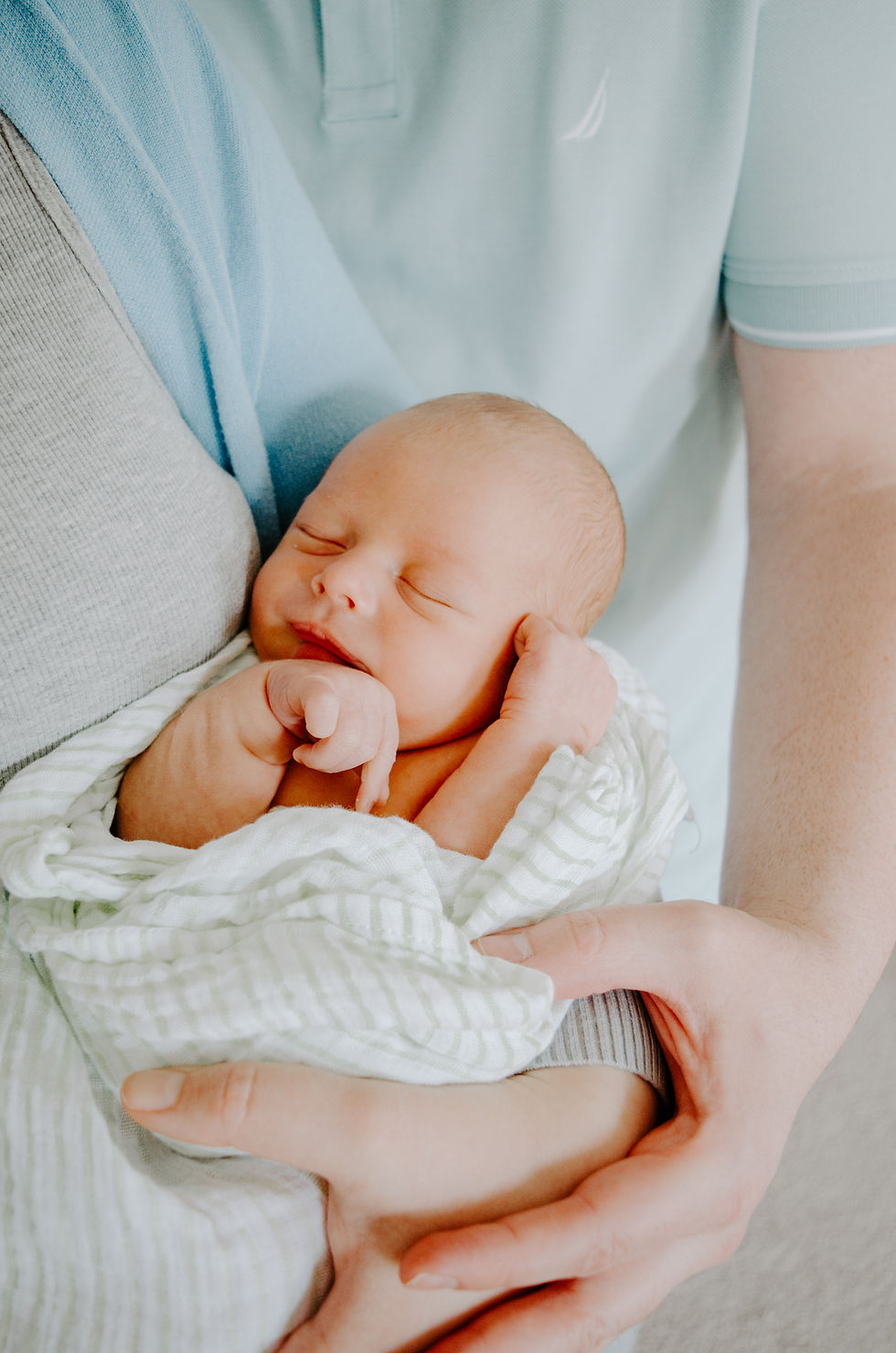a baby sleeping in his mothers arms, wrapped in a blanket