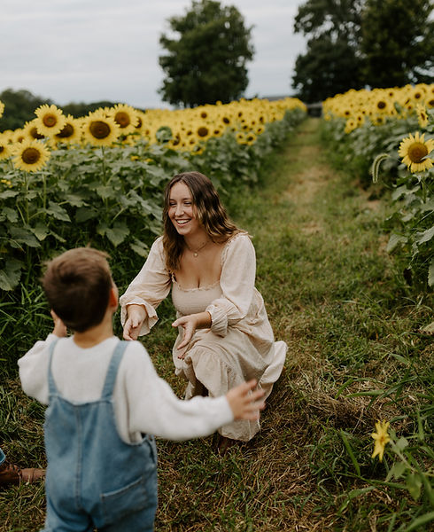 a young boy running to embrace his mom in a sunflower field.