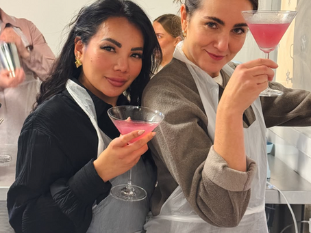 Two women holding up pink cosmopolitan cocktails during a hen party at Bake Master London