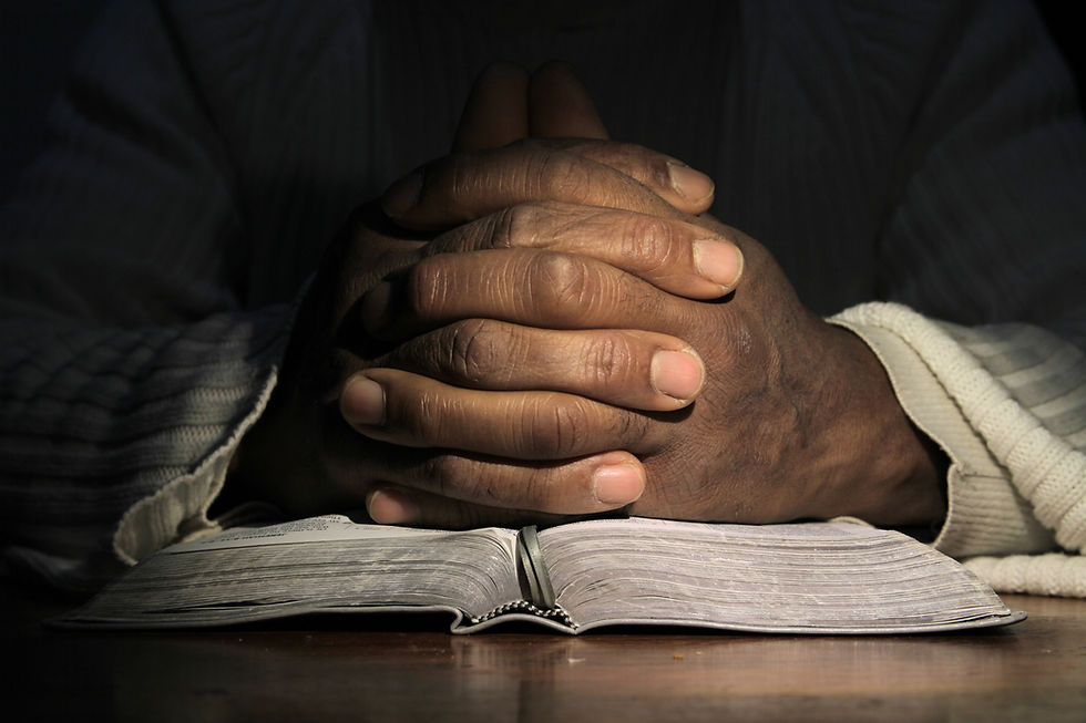 man praying with hand on bible black background stock photo.jpg