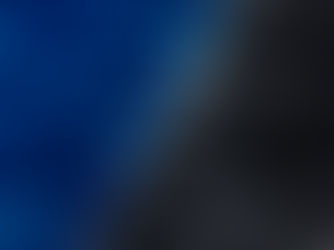 Tennis court with blue and black sections. Chain-link shadows create patterns on the surface. Bright sunlight casts contrasting shadows.