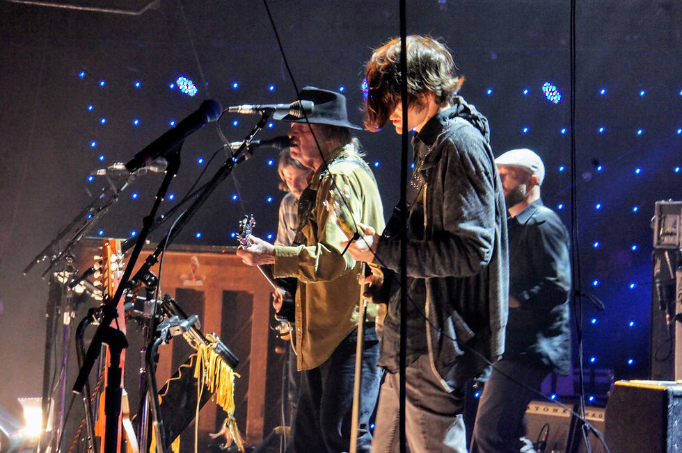 Neil Young performing at Farm Aid 2015 in Chicago, flanked by Willie Nelson's sons Micah (foreground) and Lukas (background). Micah now performs with Chrome Hearts, Young's current band. Photo by Bob Benenson