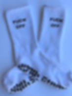 Thumbnail: Close-up of white grip socks laid flat, focusing on the ribbed fabric and bold text near the cuff.