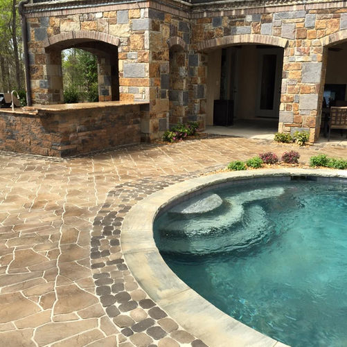 Large stone patio with an outdoor bar and pool