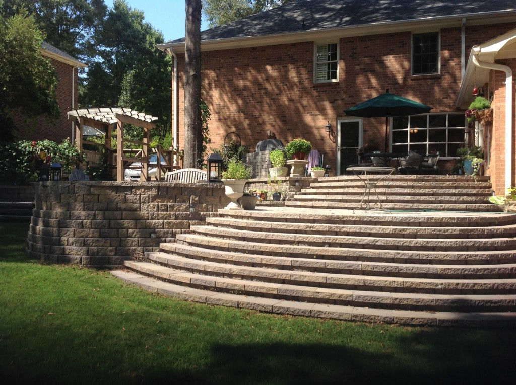 Large tiered stone patio with wide curved steps and pergola