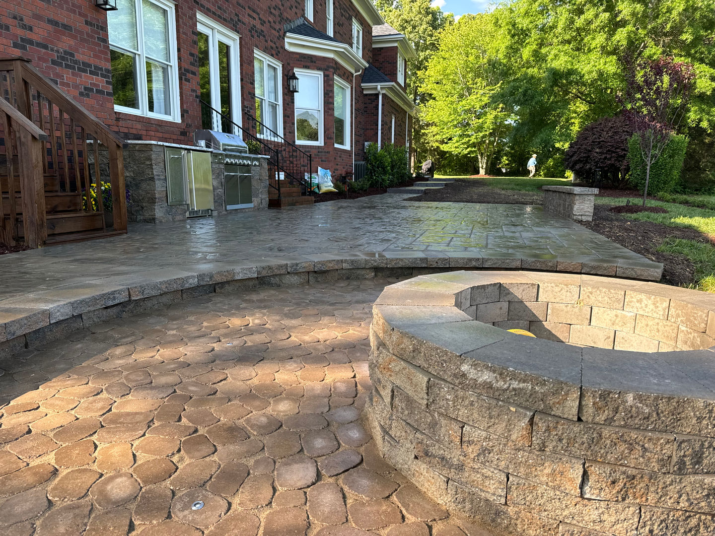 Large stone patio with fire pit and brick house exterior