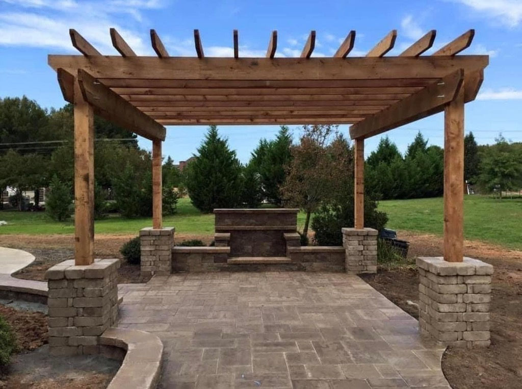Large patio with stone pavers and a wooden pergola.