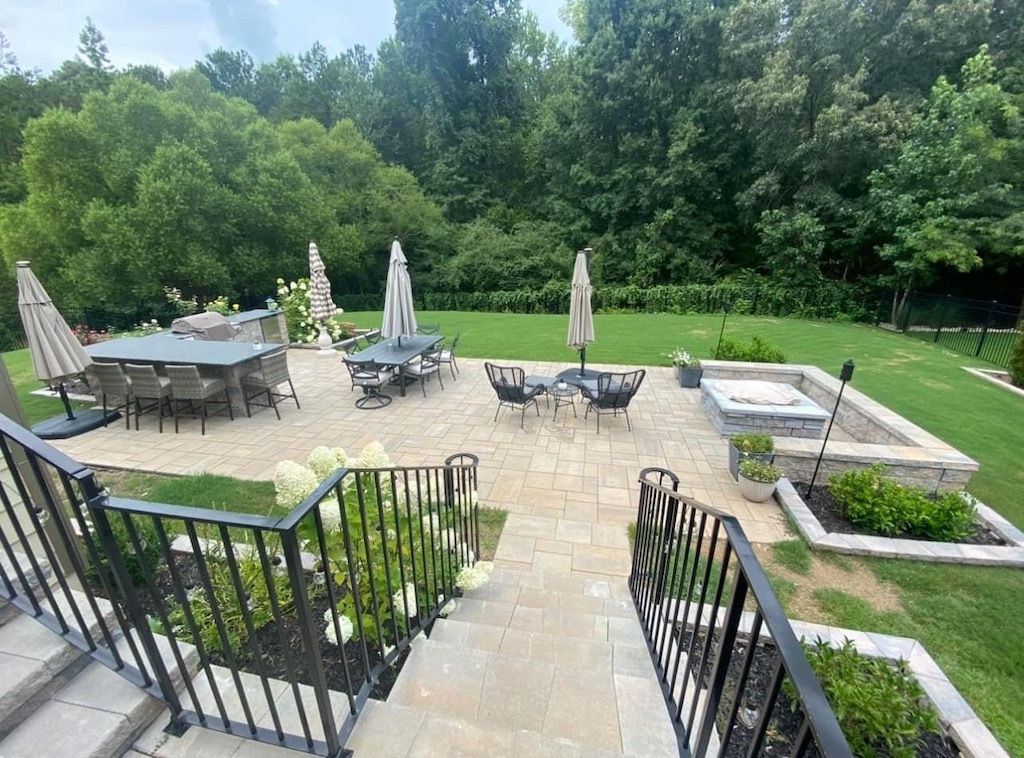 Large stone patio with multiple dining sets and umbrellas.