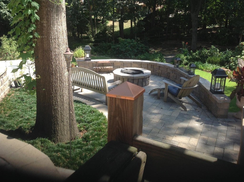 Large patio with stone fire pit, curved wall, and seating.