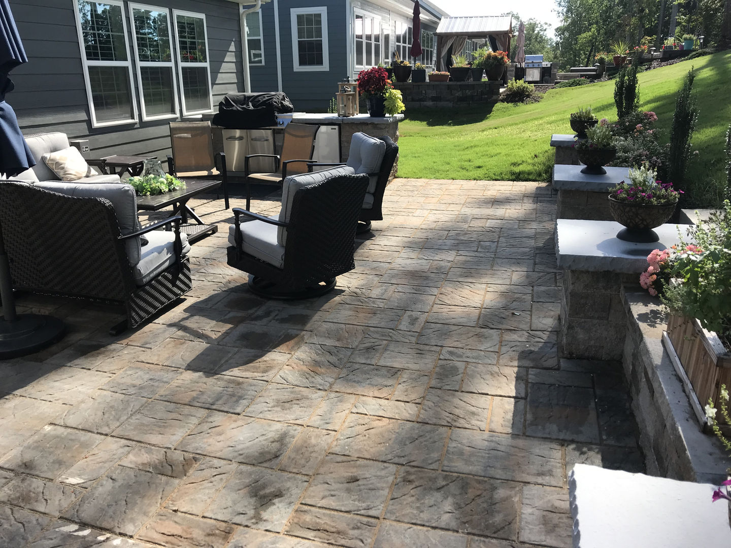 Stone patio with outdoor seating and a grassy lawn.