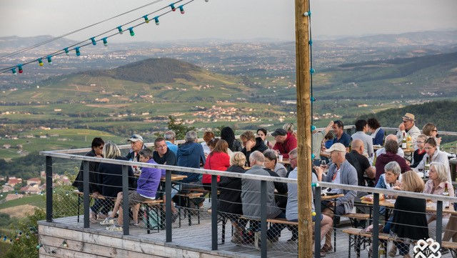 people on a terrasse enjoying alfresco dining and wine tasting in Beaujolais wine region