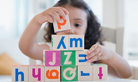 Young girl stacking alphabet blocks
