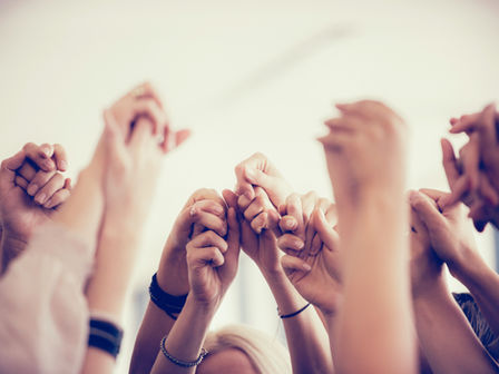 A group of holding hands raised into the air.